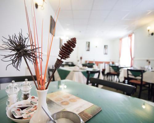 a table with a vase with some sticks in it at Pearl Hotel in Blackpool