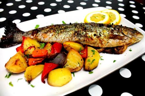 a fish on a plate with potatoes and vegetables at Hotel Bucegi Portile Regatului in Paraul Rece