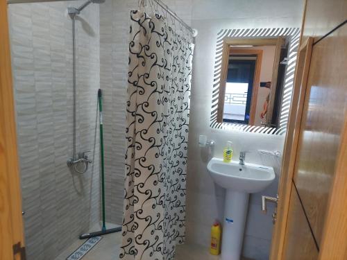 a bathroom with a shower curtain and a sink at Ghougine Serenity Residence Bis in Tangier