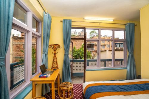 a bedroom with a bed and a balcony with windows at Kwabahal Boutique Hostel in Kathmandu