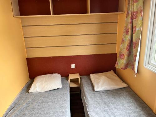 a small room with two beds and a window at Camping De Collignon in Cherbourg en Cotentin