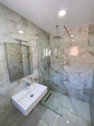uma casa de banho com um lavatório e um chuveiro em Eraldo's Rooms and Apartments em Sarandë