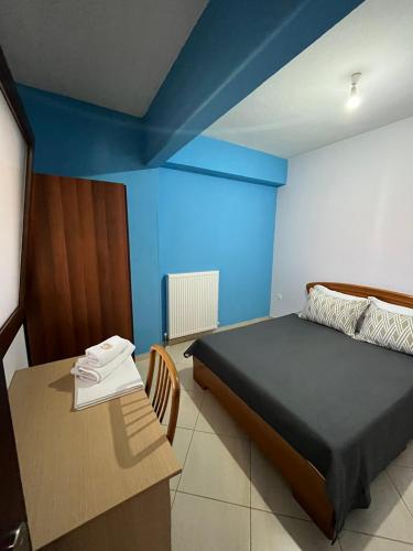 a bedroom with a bed and a table and blue walls at HIPPOCAMPUS APARTMENT in Stratónion