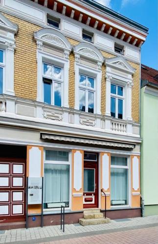 um edifício com portas vermelhas e janelas numa rua em Ferienwohnung Karpe em Schwedt