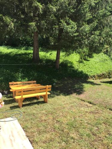 a wooden bench sitting in the grass in a park at Apartman Kosuta Lux in Tjentište