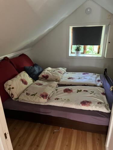 uma cama com duas almofadas e uma janela num quarto em Koselig lite hus nær sentrum em Arendal