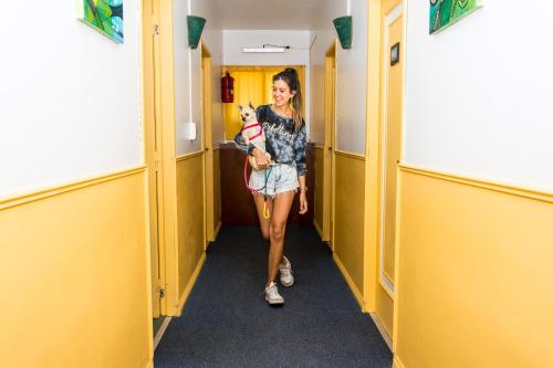 Una mujer caminando por un pasillo con su perro en Hosteria Dalmacia en Pinamar