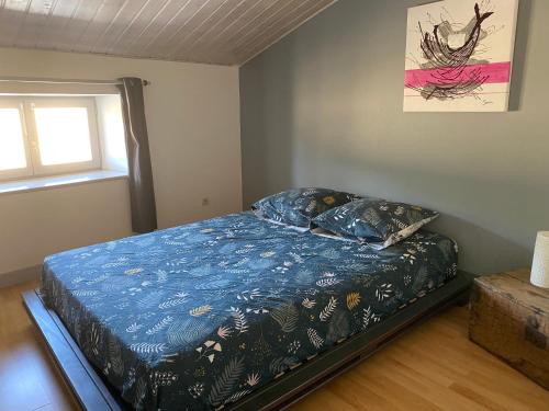 une chambre avec un lit avec une couette bleue et une fenêtre dans l'établissement Appartement Amarante, à Puy-Saint-Martin