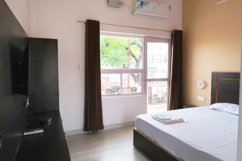 ein Schlafzimmer mit einem Bett und einem großen Fenster in der Unterkunft Aarambh Residency in Khajurāho