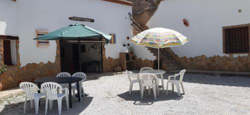 a patio with tables and chairs and an umbrella at Cuevas Lourdes in Benamaurel