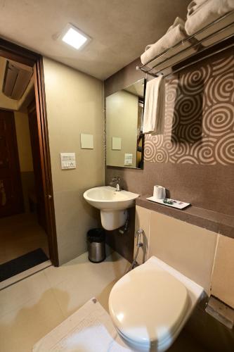 a bathroom with a toilet and a sink at Hotel Sai Inn in Mumbai