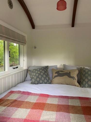 a bed with pillows on it in a bedroom at Coachroad Shepherds Huts in Petworth