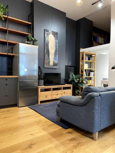ein Wohnzimmer mit einem blauen Sofa und einem Kühlschrank in der Unterkunft The Artist Residence / 1 bedroom w/ Piano next to a Park in Riga