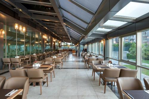 a restaurant with tables and chairs and windows at Miracle Istanbul Asia Airport Hotel & Spa in Istanbul