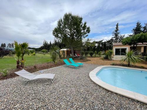 une cour avec une piscine et deux chaises ainsi qu'une maison dans l'établissement Villa au calme avec piscine chauffée, à Châteaurenard