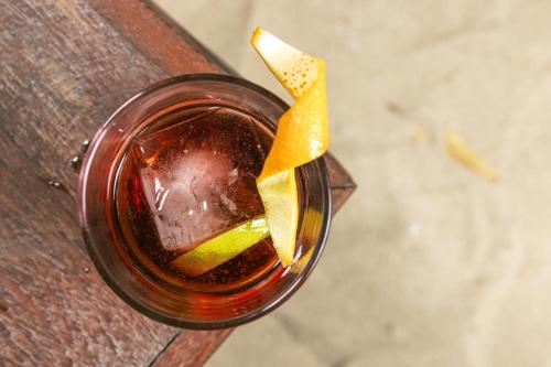 a drink with an orange slice on a wooden table at La Cozinha Bungalow in Barra Grande