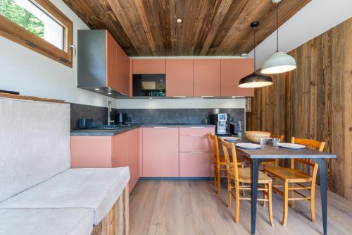 une cuisine avec des placards roses et une table avec des chaises dans l'établissement Riante 6 - Appartement proche du village et des pistes, à La Clusaz