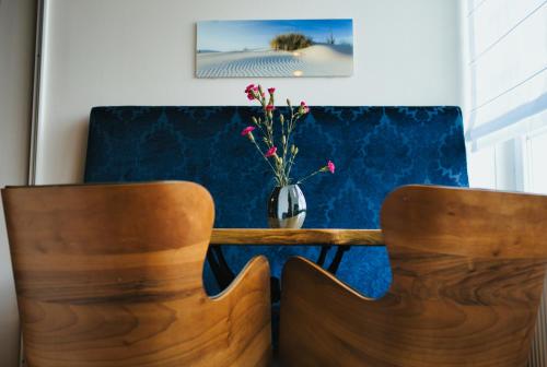 two wooden chairs and a table with a vase of flowers at Residence Black Eagle Lubmin Strand in Lubmin