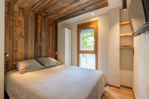 une chambre avec un grand lit et une fenêtre dans l'établissement Riante 6 - Appartement proche du village et des pistes, à La Clusaz