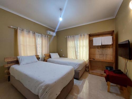 a bedroom with two beds and a television in it at Maili 6 Private Apartments in Moshi