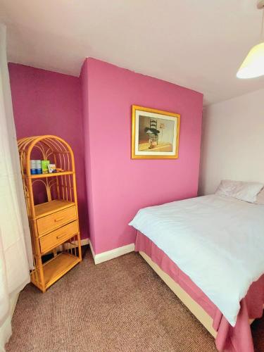 a bedroom with a pink wall with a bed and a shelf at Liverpool Newington Stay in Liverpool
