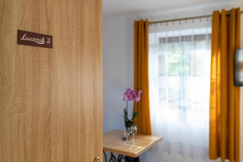 a door with a sign on it next to a vase of flowers at Dom Krawca - pod Chojnikiem in Jelenia Góra