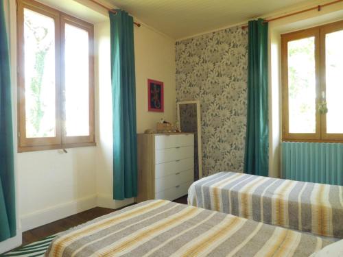 a bedroom with two beds and two windows at Gite de France Lacam in Bannes