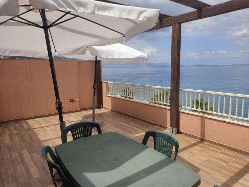 einen Tisch und Stühle auf einem Balkon mit Sonnenschirm in der Unterkunft veranda sul mare in Bagnara Calabra
