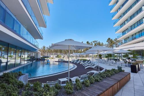 an outdoor pool with chairs and umbrellas and a pool at Wave Prestige Sea View - SPA&Pools in Międzyzdroje