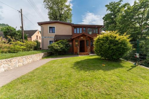 a house with a stone wall and a yard at Dom Krawca - pod Chojnikiem in Jelenia Góra
