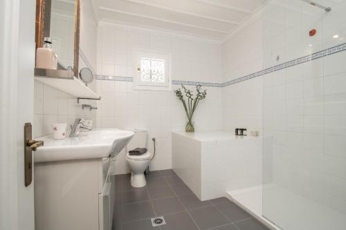 La salle de bains blanche est pourvue de toilettes et d'un lavabo. dans l'établissement Villa Verdi - Your Family Oasis!, à Vasilikos