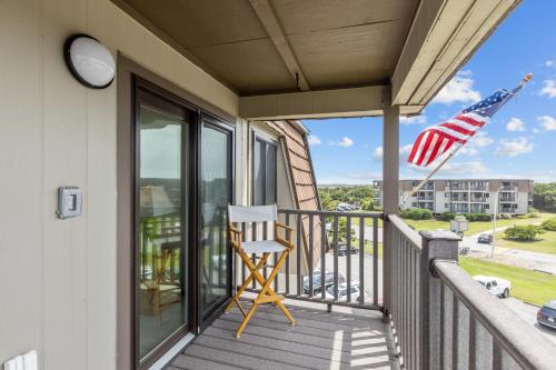 a chair on a porch with an american flag at Southwinds, Unit H13 in Atlantic Beach