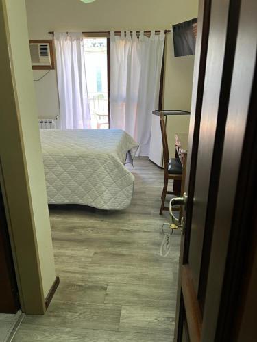 a bedroom with a bed and a table and a window at Hotel Catedral in Luján