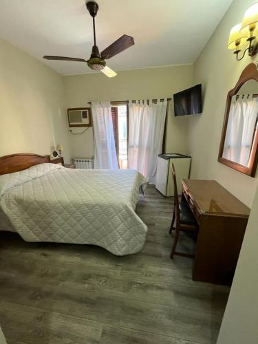a bedroom with a bed and a desk and a ceiling fan at Hotel Catedral in Luján