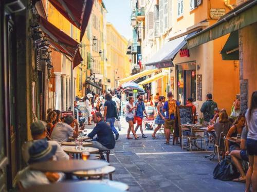a group of people sitting at tables on a street at Beautiful flat with sunny balcony in heart of Nice Le Port in Nice