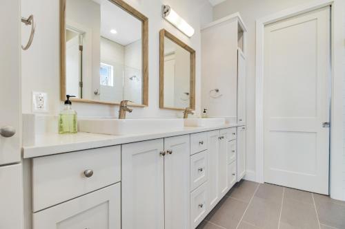 een witte badkamer met 2 wastafels en spiegels bij White Orchard at The Reserve in Spicewood
