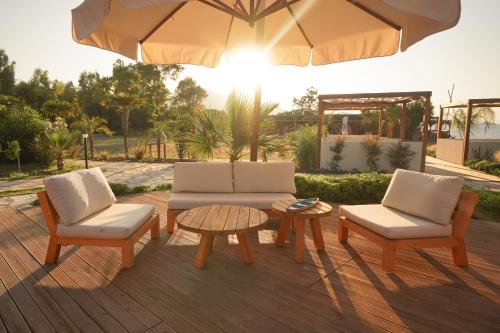 a patio with two chairs and a table and an umbrella at Datça Dirik Surf Beach Hotel in Datca