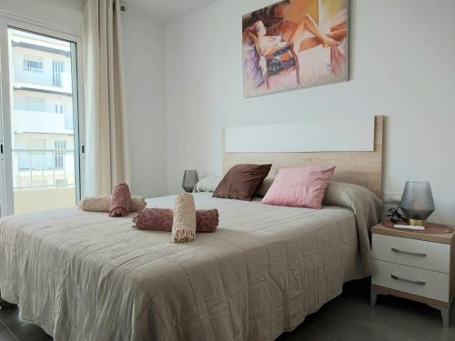1 dormitorio con 1 cama grande con almohadas rosas en App.Pradomar Peñiscola, en Peñíscola