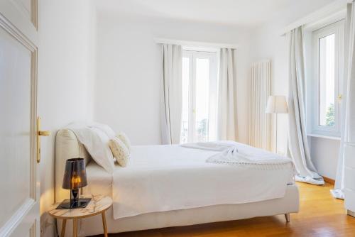 a white bedroom with a white bed and windows at Villa Magnolia - High standing floor in Locarno