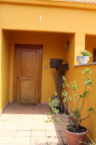 ein gelbes Gebäude mit einer Holztür und einigen Pflanzen in der Unterkunft Chalet en Comillas in Comillas