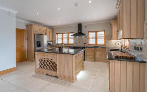 a large kitchen with wooden cabinets and black counter tops at The Hoose at The Vu in Bathgate