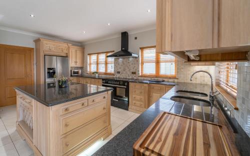 a large kitchen with wooden cabinets and a sink at The Hoose at The Vu in Bathgate