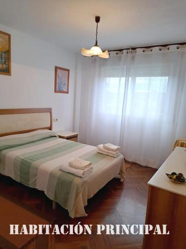 a bedroom with two beds and a window at Piso al lado de la estación de tren y de la playa, con dos plazas de garage in Vilagarcia de Arousa