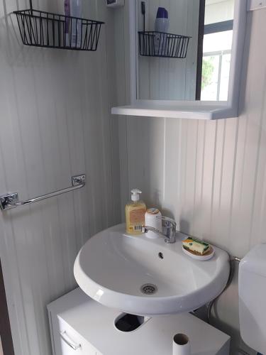 a white bathroom with a sink and a mirror at Mobile Home Marta in Senj