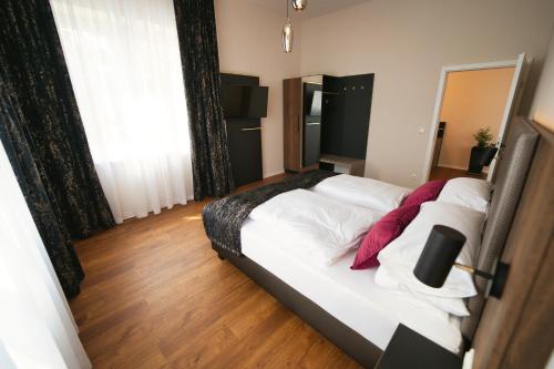a bedroom with a bed with white sheets and red pillows at Residence Black Eagle Lubmin Strand in Lubmin