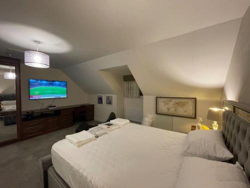 a bedroom with a large white bed and a flat screen tv at MODERN 4 BEDROOM HOUSE WITH GARDEN & PARKING in Swanscombe