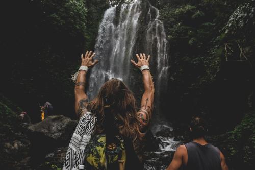 a woman standing in front of a waterfall at Desa Eko in Munduk