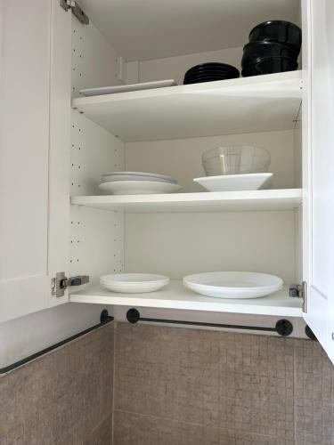 a kitchen with white plates and bowls on shelves at Sunhaus in Gdynia