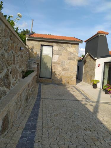 a stone house with a stone wall and a sidewalk at CASA DAS FONTELAS in Castelo de Paiva