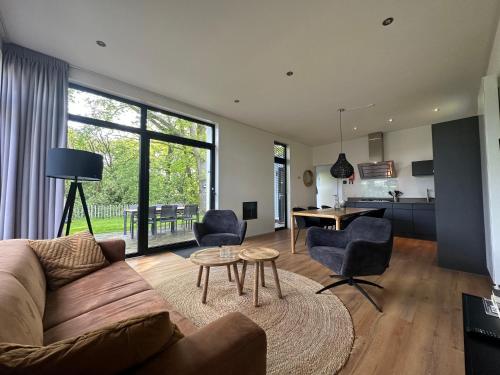 een woonkamer met een bank, stoelen en een tafel bij BadHoophuizen 6-per Bungalow Veluwemeer Trampoline in Hulshorst